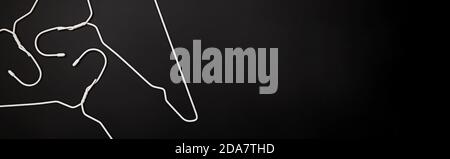 Empty white hangers lying on black background Stock Photo