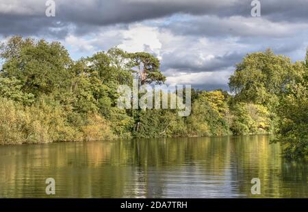 Trees are reflected in the River Thames in this photo taken on a clear autumn day near Egham in Surrey Stock Photo