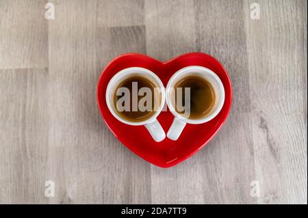 two cups of coffee with a red ceramic heart saucer Stock Photo