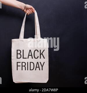 Crop view of woman hand holding paper shopping bag by handles on red background Stock Photo