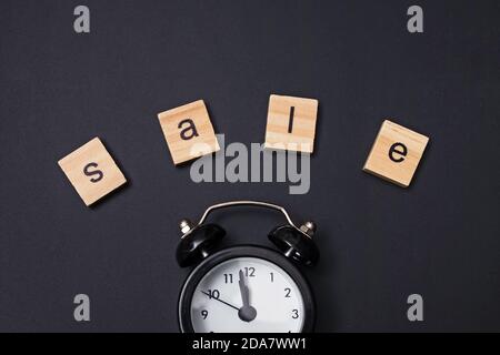 Small alarm clock and word Sale on black background Stock Photo