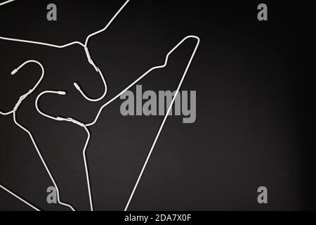 Empty white hangers lying on black background Stock Photo