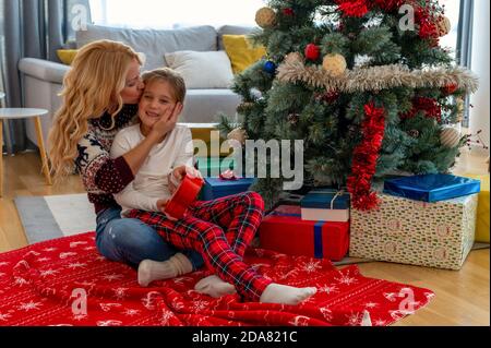 Closeup of a happy mother kissing her daughter, Christmas mood in a cozy house Stock Photo