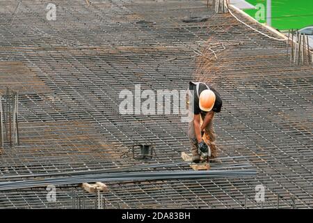 The employee works on the construction site. Performed work electric tools for cutting reinforcement. Stock Photo