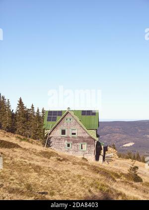 Retro toned picture of mountain hut with solar panels on roof. Stock Photo