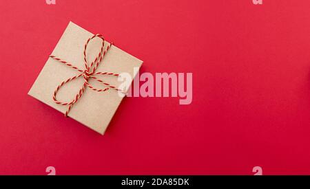 Festive composition with gift box on red background, layout with space for text. Paper box with ribbon, top view Stock Photo