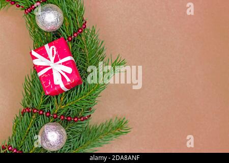 Border frame of traditional green noble fir tree with Christmas balls, gift boxes and garlands on craft paper background with copy space. Flatlay. Stock Photo