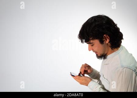 Young Hispanic man with casual clothes on a white background using a cell phone very happy Stock Photo