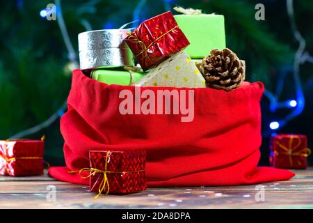 Santa Claus bag with gifts on a wooden table against the background of a decorated Christmas tree Stock Photo