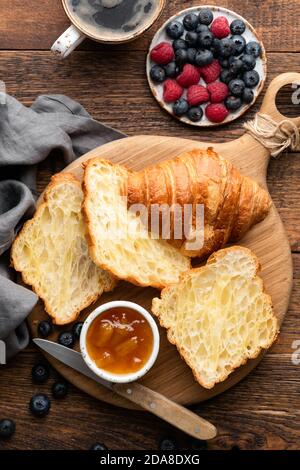 French croissants with berries and jam on a wooden background, top view. Halved croissants, croissant texture Stock Photo