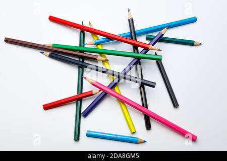 top view of a chaotic pile of color pencils, looking like mikado game on white and uniform background Stock Photo