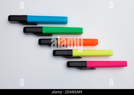 Top view of  highlighter pens with closed caps in neon clolors on white uniform background, diagonal row pattern, use for business presentations and m Stock Photo