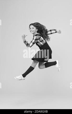 Break into. Feel inner energy. Girl with long hair jumping on yellow background. Carefree kid summer holiday. Time for fun. Active girl feel freedom. Fun and jump. Happy childrens day. Jump concept. Stock Photo