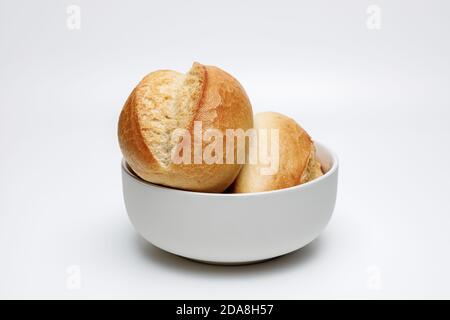Two typical german wheat buns in a white ceramic bowl on a white uniform background, gold baked buns are typical baked in germany Stock Photo