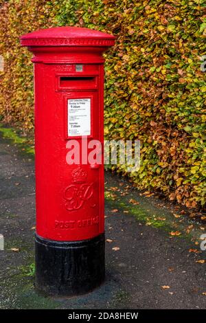 Royal Mail postbox - a red King George VI red pillar post box in Cambridge UK. Traditional British Pillar Box. Stock Photo