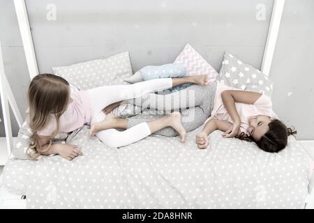 having fun together. fun before sleep. best friends. sisters playing in bed. sweet dreams. pajama party in bedroom. childhood happiness. kids friendship. happy small girls. good morning. Stock Photo
