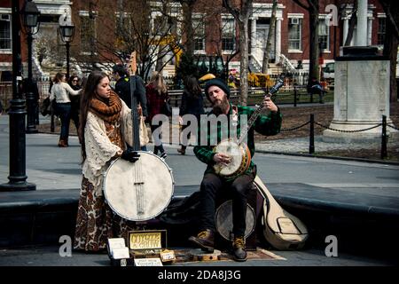 Married couple Coyote & Crow playing bluegrass on 5-string banjo and one-of-a-kind bass banjo in Washington Square Park, Greenwich Village, NYC. NY Stock Photo