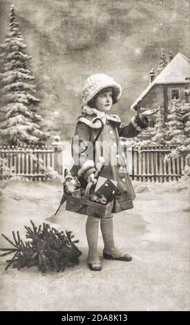 Little girl with christmas tree, gifts and vintage toys. Old postcard with original film grain and scratches Stock Photo