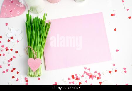 Romantic background in pink tones with hearts, pink envelope and green bouquet on a light background. Stock Photo