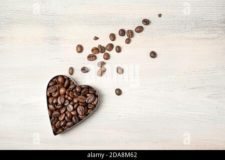 Heart of coffee beans in the shape of a flying comet on a light background. Top view with space to copy. Stock Photo