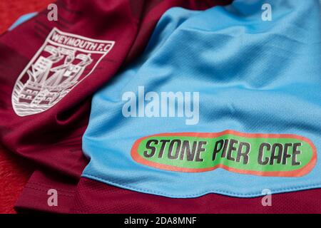 Stone Pier Cafe sponsorship logo next to the Weymouth Football Club Badge on the Weymouth FC Women's home shirt. Stock Photo