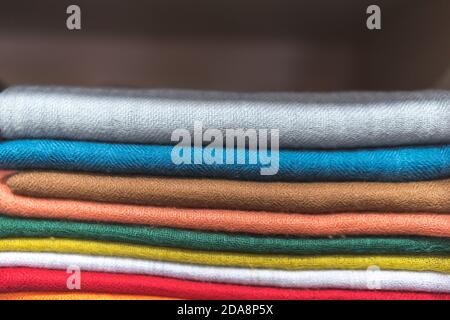 folded scarfs on the shelf, close up of colourful fabric, a pile of cashmere textile, stack of colourful clothes, a pile of clothes Stock Photo