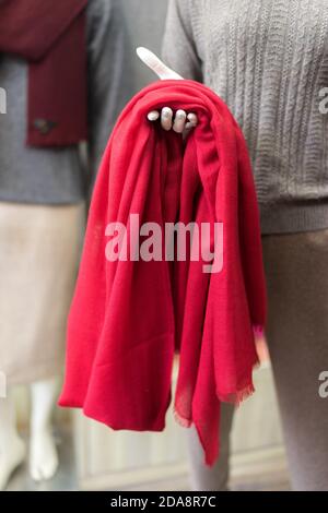 clothes in a shop, red cashmere scarf in a showroom, clothing store, woollen products, mannequin exposing elegant classic cloth, piece of red textile Stock Photo