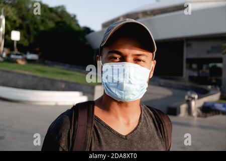 Portrait of young African man with a medical protective mask on his face at city street. Concept of preventive measures and protection for coronavirus Stock Photo