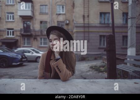 sad Ukrainian young girl sitting on a bench in the yard of his apartment building Stock Photo