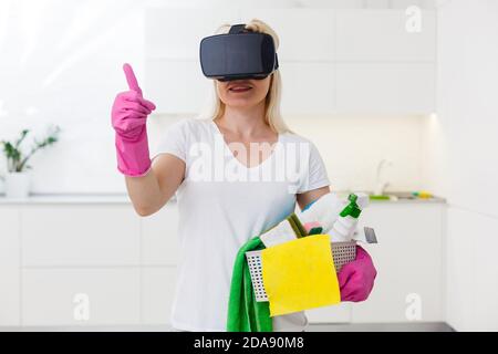 beautiful pretty housewife wearing VR device on living room looking 3D video using hand touching simulation to view house design. Stock Photo