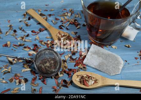 image of infusion leaves, wooden spoon and cup of tea on blue background table Stock Photo