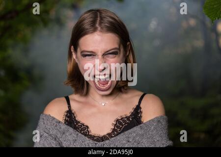 Young girl screaming in a dark forest Stock Photo