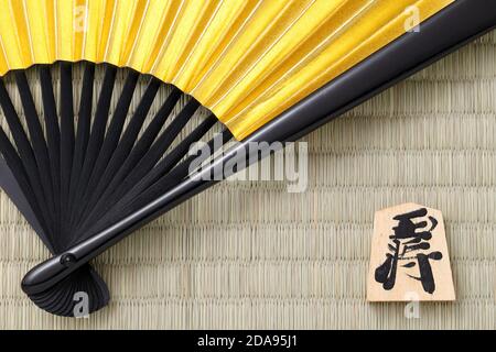 Japanese Shogi pieces and Sensu on a Tatami background, Shogi is Japanese chess. Word that is written in the piece is king. Stock Photo