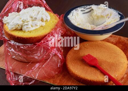 Technique of cake assembly. Whipped cream in bowl and sponge cake. Stock Photo