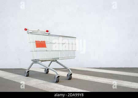 Empty Grocery Cart on the White Wall Store. Trolley at the Supermarket Background. E-commerce. Shopping Concept. Side View. Shopping Cart Trolley Stock Photo