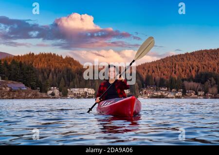 Adventurous Girl Paddling on a Bright Red Kayak Stock Photo