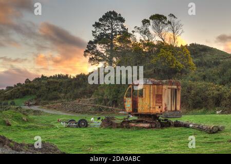 An old abandoned crawler crane, a type of construction vehicle, rusting on a farm Stock Photo