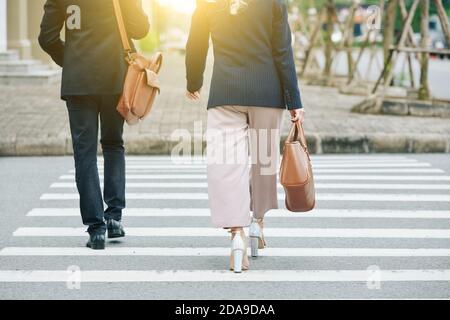 Business people crossing road, view from the back Stock Photo