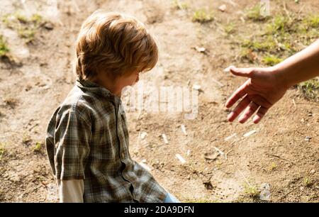 Father giving son a helping hand, hope and support children. A crying toddler sit down on the road. Kids with tears emotional. Upset child. Violence Stock Photo