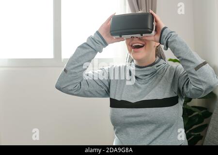 Excited pregnant young woman trying to play videogame in virtual reality headset for the first time Stock Photo