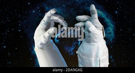 Bright stars in a night sky arranged in the shape of a heart, heart galaxy  in astronaut hands. Love shape astronaut hands. Elements of this image fur Stock Photo