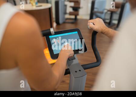 Close up picture of a persons hand pressing a touchpad on a gym machine Stock Photo