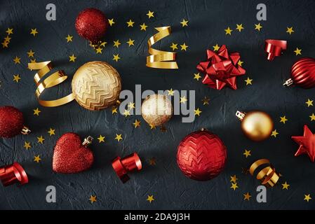 Christmas composition. Red and golden christmas baubles and festive ribbons on a dark background, top view Stock Photo