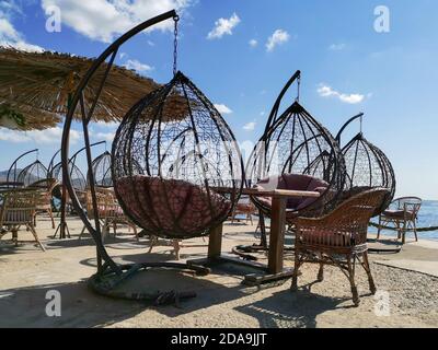 Outdoor terrace with Empty wooden table and chair with Sea view. Hanging chairs, table at the terrace, umbrella from the sun. Stock Photo
