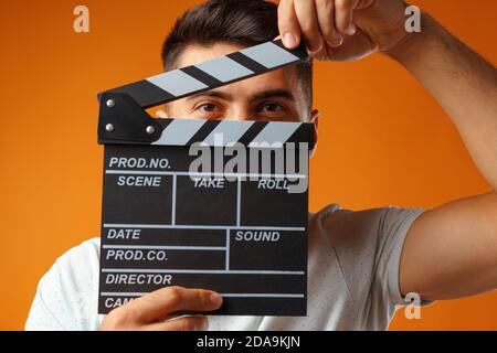 Young man holding Film clapper board against yellow background Stock Photo