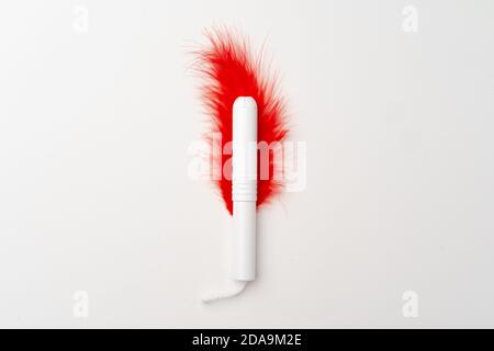 Red feather and woman medical tampon on white background Stock Photo