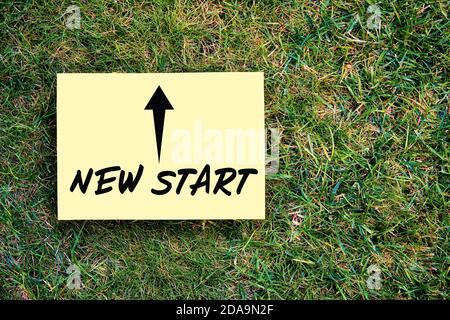 The words new start motivational message written on paper on green grass background. Inspirational quote to create a new future or beginning in busine Stock Photo