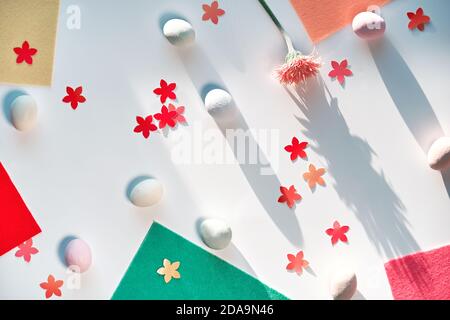 Easter background with eggs, floral confetti and felt for craft projects. Top view, long shadows. Stock Photo