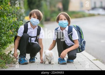 School children, boys, going back to school after the summer vacation, kids going to school wearing medical mask due to coronavirus COVID 19 Stock Photo