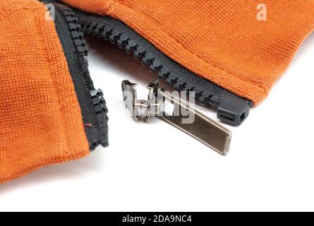 Broken zipper on orange shirt jacket. Detail close-up photo. Clothing repair concept Stock Photo